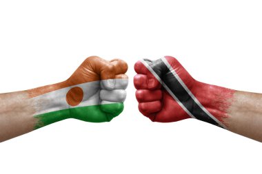 Two hands punch to each others on white background. Country flags painted fists, conflict crisis concept between niger and tobago
