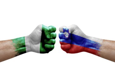 Two hands punch to each others on white background. Country flags painted fists, conflict crisis concept between nigeria and slovenia