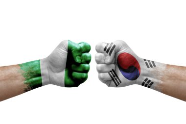 Two hands punch to each others on white background. Country flags painted fists, conflict crisis concept between nigeria and south korea