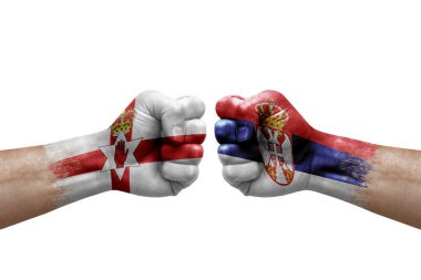 Two hands punch to each others on white background. Country flags painted fists, conflict crisis concept between northern ireland and serbia