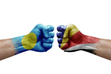 Two hands punch to each others on white background. Country flags painted fists, conflict crisis concept between palau and seychelles
