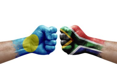 Two hands punch to each others on white background. Country flags painted fists, conflict crisis concept between palau and south africa