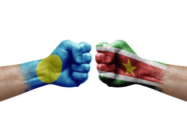 Two hands punch to each others on white background. Country flags painted fists, conflict crisis concept between palau and suriname