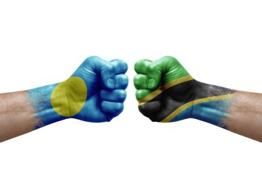 Two hands punch to each others on white background. Country flags painted fists, conflict crisis concept between palau and tanzania