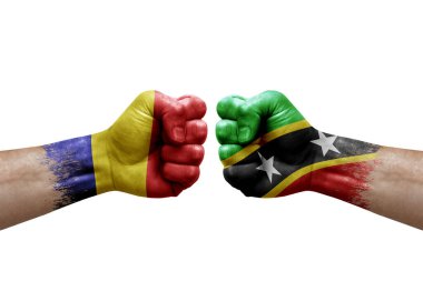 Two hands punch to each others on white background. Country flags painted fists, conflict crisis concept between romania and saint kitts and nevis