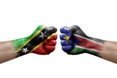 Two hands punch to each others on white background. Country flags painted fists, conflict crisis concept between saint kitts and nevis and south sudan