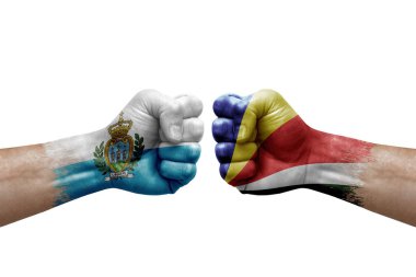 Two hands punch to each others on white background. Country flags painted fists, conflict crisis concept between san marino and seychelles
