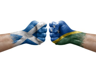 Two hands punch to each others on white background. Country flags painted fists, conflict crisis concept between scotland and solomon islands