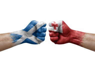 Two hands punch to each others on white background. Country flags painted fists, conflict crisis concept between scotland and tonga