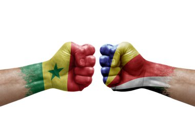 Two hands punch to each others on white background. Country flags painted fists, conflict crisis concept between senegal and seychelles