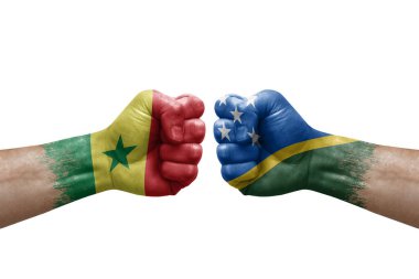 Two hands punch to each others on white background. Country flags painted fists, conflict crisis concept between senegal and solomon islands