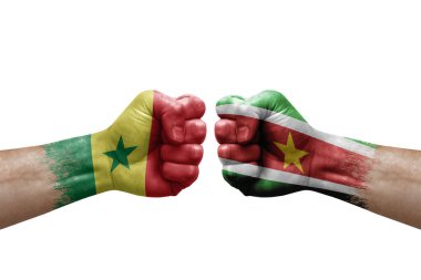 Two hands punch to each others on white background. Country flags painted fists, conflict crisis concept between senegal and suriname
