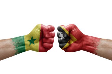 Two hands punch to each others on white background. Country flags painted fists, conflict crisis concept between senegal and timor leste