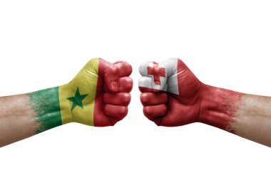 Two hands punch to each others on white background. Country flags painted fists, conflict crisis concept between senegal and tonga