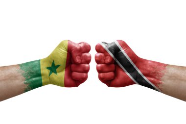 Two hands punch to each others on white background. Country flags painted fists, conflict crisis concept between senegal and tobago