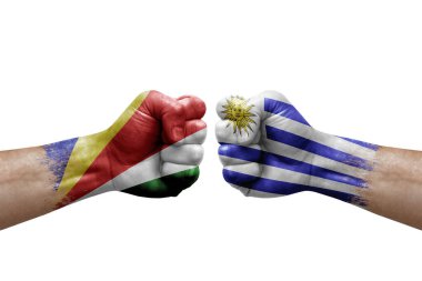 Two hands punch to each others on white background. Country flags painted fists, conflict crisis concept between seychelles and uruguay