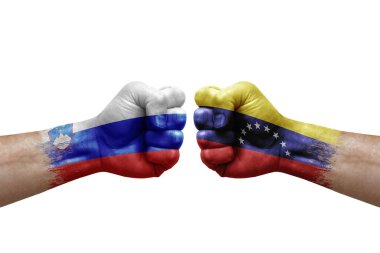 Two hands punch to each others on white background. Country flags painted fists, conflict crisis concept between slovenia and venezuela