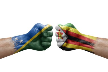 Two hands punch to each others on white background. Country flags painted fists, conflict crisis concept between solomon islands and zimbabwe