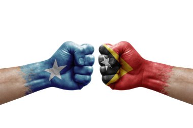 Two hands punch to each others on white background. Country flags painted fists, conflict crisis concept between somalia and timor leste