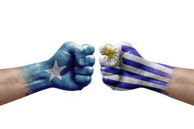 Two hands punch to each others on white background. Country flags painted fists, conflict crisis concept between somalia and uruguay