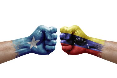 Two hands punch to each others on white background. Country flags painted fists, conflict crisis concept between somalia and venezuela