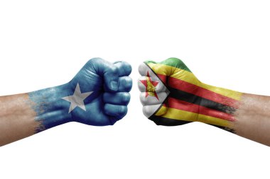 Two hands punch to each others on white background. Country flags painted fists, conflict crisis concept between somalia and zimbabwe