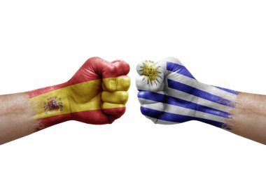 Two hands punch to each others on white background. Country flags painted fists, conflict crisis concept between spain and uruguay