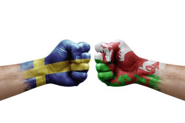 Two hands punch to each others on white background. Country flags painted fists, conflict crisis concept between sweden and wales