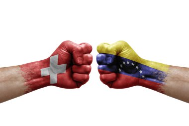 Two hands punch to each others on white background. Country flags painted fists, conflict crisis concept between switzerland and venezuela