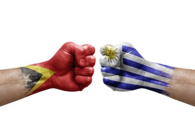 Two hands punch to each others on white background. Country flags painted fists, conflict crisis concept between timor leste and uruguay