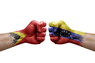 Two hands punch to each others on white background. Country flags painted fists, conflict crisis concept between timor leste and venezuela