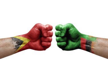Two hands punch to each others on white background. Country flags painted fists, conflict crisis concept between timor leste and zambia