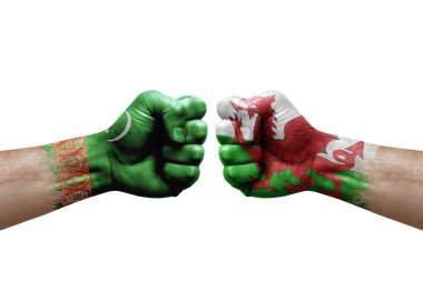 Two hands punch to each others on white background. Country flags painted fists, conflict crisis concept between turkmenistan and wales