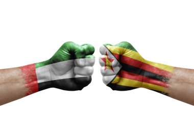 Two hands punch to each others on white background. Country flags painted fists, conflict crisis concept between uae and zimbabwe