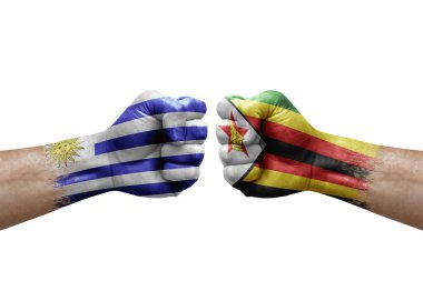 Two hands punch to each others on white background. Country flags painted fists, conflict crisis concept between uruguay and zimbabwe
