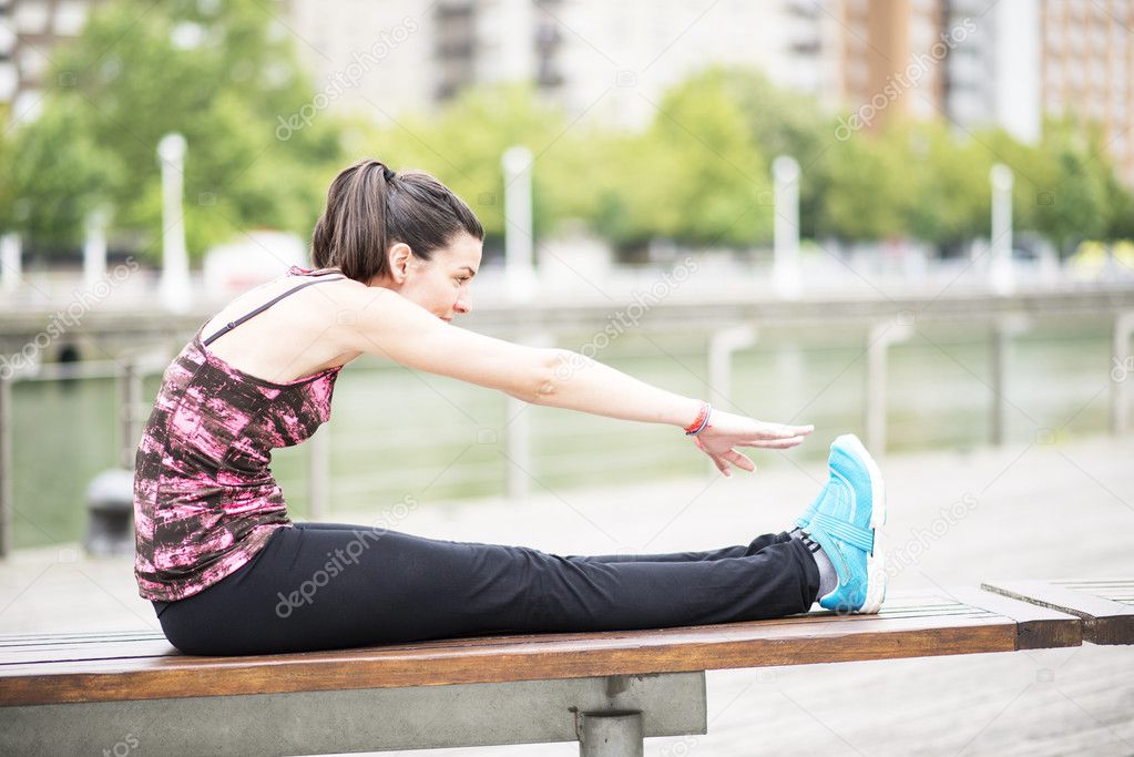 Young Woman Doing Stretches on wooden bench.