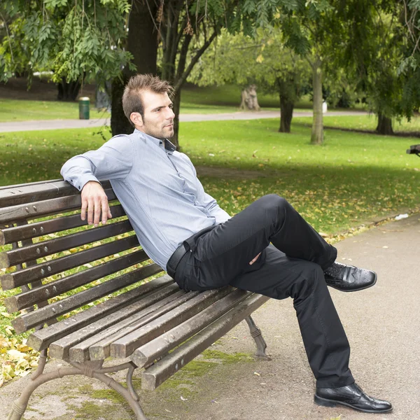 Man zittend op een bankje in het park. — Stockfoto