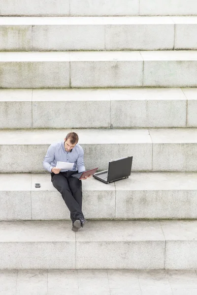 Podnikatel sedí na kroky a přenosný počítač. — Stock fotografie
