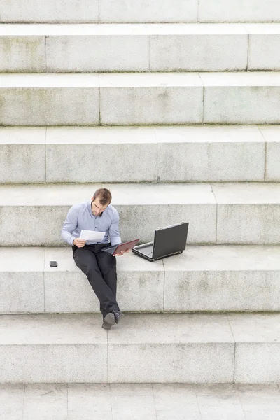 Empresario sentado en los escalones y ordenador portátil . — Foto de Stock