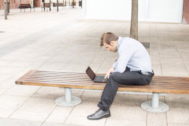 işadamı dizüstü bilgisayar sokakta bir banka ile.