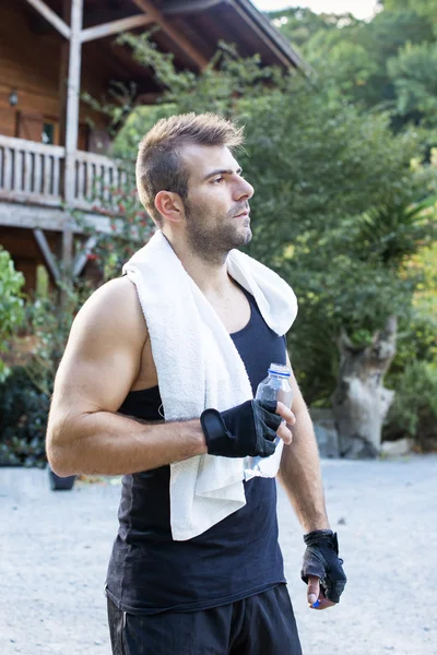 Portrét sportovní člověka s ručníky a láhev vody. — Stock fotografie
