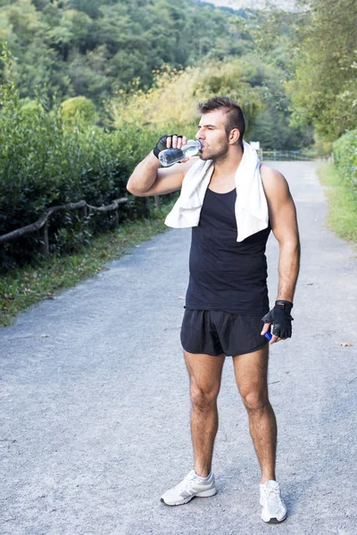 Su şişesi açık sonra onun egzersiz ile atletik erkek. — Stok fotoğraf