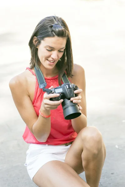 Mujer sonriente usando su cámara fotográfica . — Foto de Stock