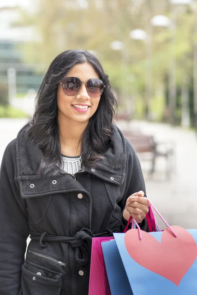 Sorrindo mulher atraente com óculos de sol e sacos de compras . — Fotografia de Stock