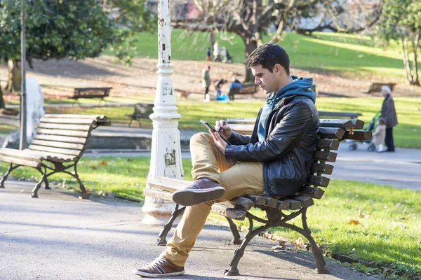 Man zitten en met behulp van tablet pc in het park. — Stockfoto