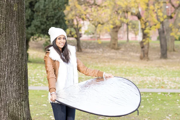 Menina sorridente posando para a câmera com o refletor, ao ar livre . — Fotografia de Stock