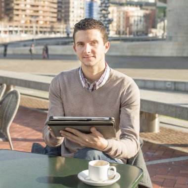 Teras bar kahve fincanı ve laptop ta oturan işadamı