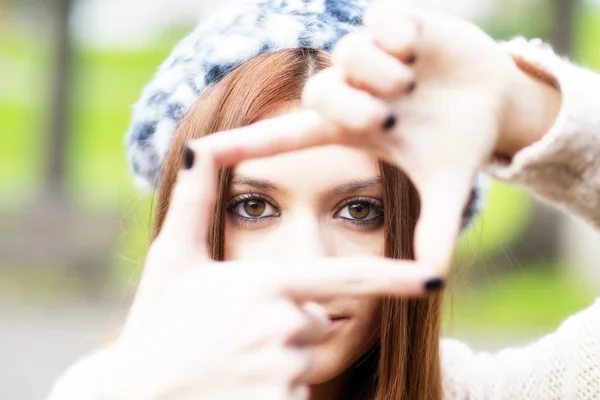 Portret van een jong meisje maken frame met haar handen, close-up. — Stockfoto