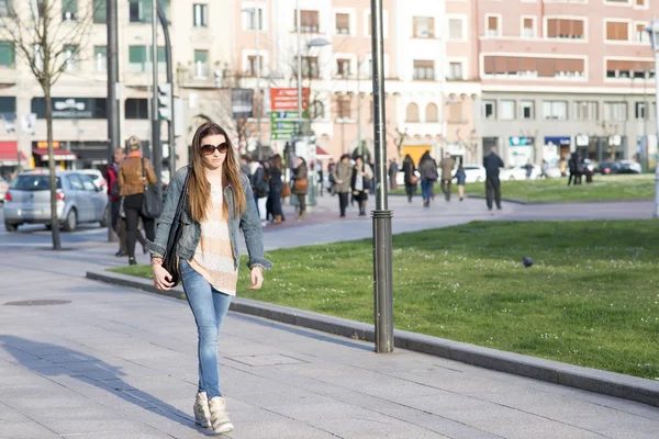 Jovem mulher caminhando pela multidão na rua . — Fotografia de Stock