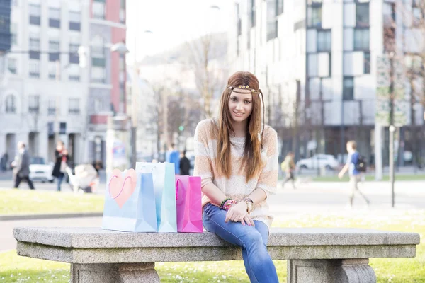 Lachende hippie meisje met shopping tassen in de straat. — Stockfoto